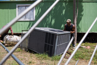 Workers remove an AC unit from a mobile home in order to tow it out of Congress Mobile Home Park in Austin, Texas, on Aug. 29, 2022. Credit: Evan L'Roy/The Texas Tribune