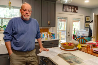 Charlie Utterback stands in his kitchen, a mine map laid in front of him. He's worried he and his wife may eventually have to leave their home of 25 years because of damage caused by mining activity. Credit: Lee Hedgepeth/Inside Climate News