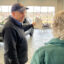 Terry Berg, who has been selling cars at Cornerstone Ford since 1987, leads a customer through the showroom at the Elk River dealership. He drives an EV and likes selling them, but finds a lot of his clients are reluctant to make the leap. Credit: Dan Gearino/Inside Climate News