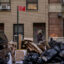 A pedestrians walks by trash bags piled on a street in Manhattan. High Acres gets about 90 percent of its waste by train from New York City. Credit: Ed Jones/AFP via Getty Images