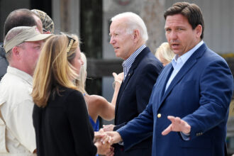 Florida Governor Ron DeSantis (right) and President Joe Biden (center) speak with local residents impacted by Hurricane Ian in Fort Myers, Fla. Credit: Olivier Douliery/AFP via Getty Images