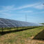 A high tension electrical power pole is seen in the background of a solar array in Blaine, Minn. Credit: Michael Siluk/UCG/Universal Images Group via Getty Images