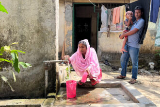 Khadiza Akhter fills up pitchers with water from a spigot in front of her home in Savar, Bangladesh. Credit: Mahadi Al Hasnat/Grist