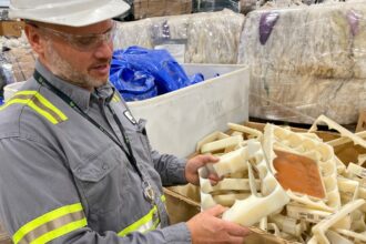 Jay Schabel, president of the plastics division at Brightmark, holds waste plastic from what he described as medical hip replacement parts at the company's new chemical recycling plant in northeast Indiana at the end of July. The plant is designed to turn plastic waste into diesel fuel, naphtha, and wax. Credit: James Bruggers