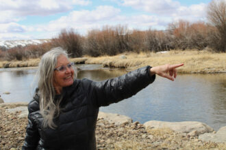 Leslie Hagenstein indicates where the New Fork River flows through her property on Mar. 27. She signed up for a program that pays her to pause irrigation on her land in order to save Colorado River water. Some experts say the System Conservation Pilot Program, or SCPP, is costly and may not be the most effective way to save Colorado River water. Credit: Alex Hager/KUNC