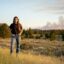 Lead plaintiff Rikki Held on her family's ranch in southeastern Montana. Behind her, a wildfire burns four miles away. In Summer 2022, this was one of 18 wildfires within 50 miles of her home.