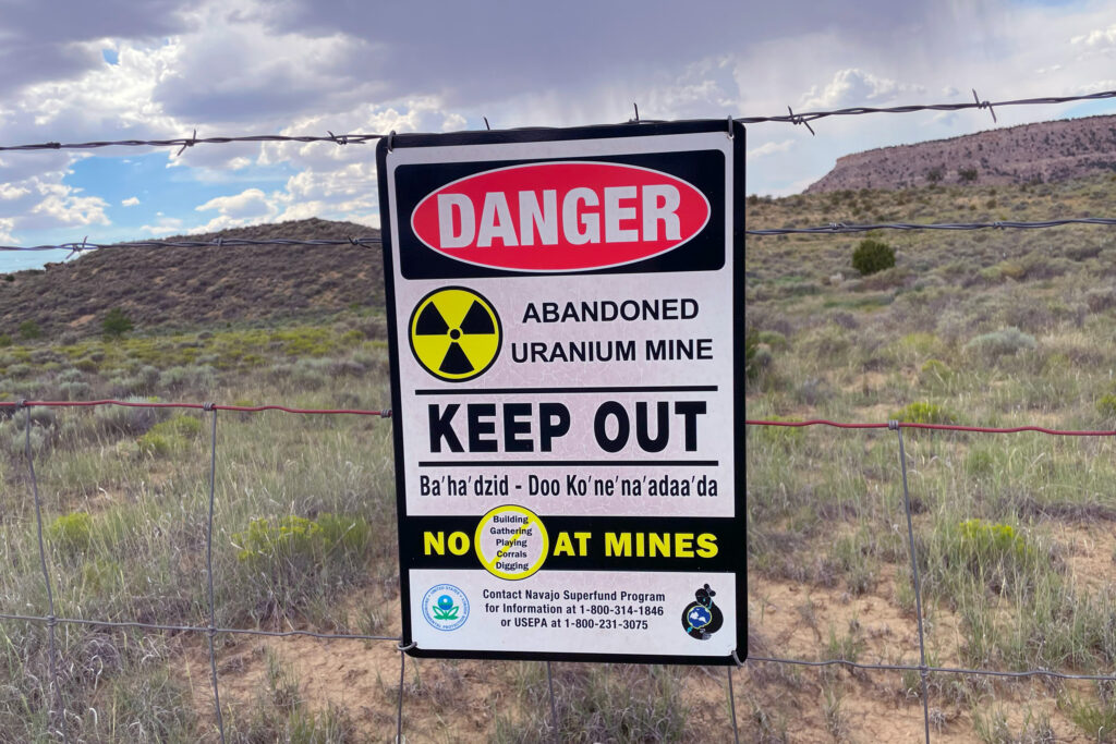 Signage written in English and the Navajo language tells the public to avoid accessing this portion of the Red Water Pond Road Community because of previous uranium mining activities. Credit: Noel Lyn Smith/Inside Climate News